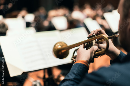 A musician playing the trumpet during a classical symphony orchestra rehearsal