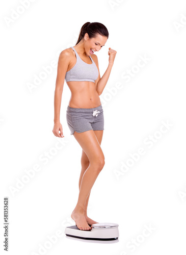Achieving her weight loss goals. Full-length shot of an attractive and sporty young woman standing on a scale.