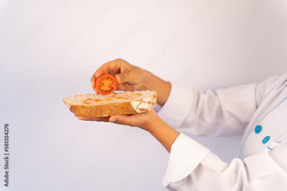 Close-up of hands with a tomato squeezing it onto a slice of rustic bread like a mediterranean style. 