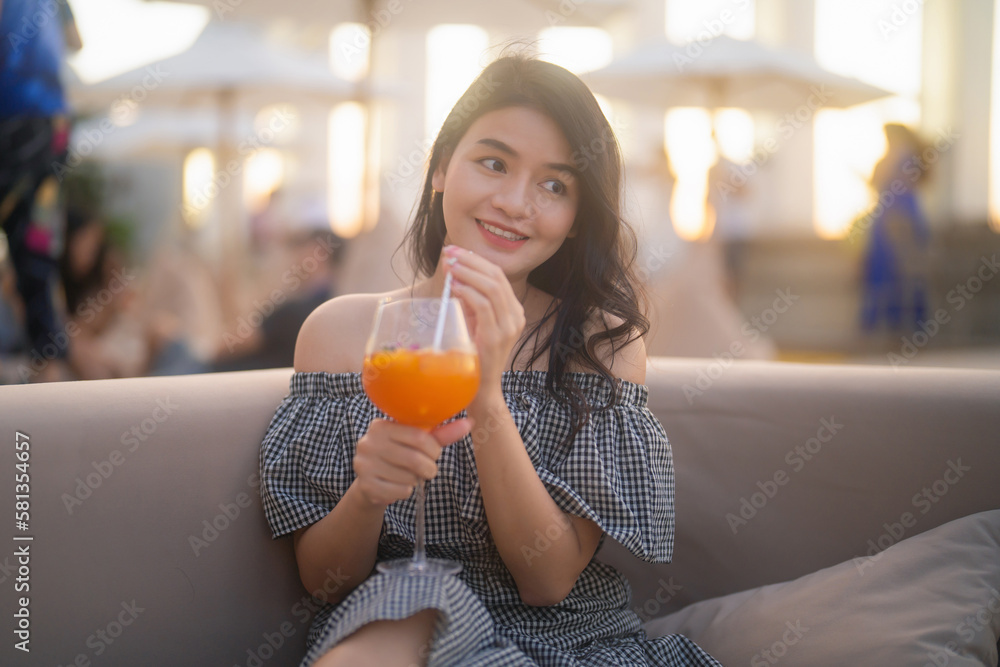 Portrait of an Asian woman holding a cocktail beer alcohol drink glass at night in restaurant on balcony sky bar with urban city skyline background. Sweet fruit food. People lifestyle. Portrait of an Asian woman holding a cocktail beer alcohol drink glass at night in restaurant on balcony sky bar with urban city skyline background. Sweet fruit food. People lifestyle.