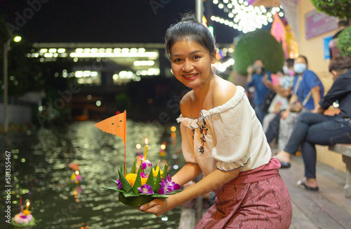 Photography Portrait of Asian Thai woman with Loy Krathong in Thailand , floating on water in local street market festival