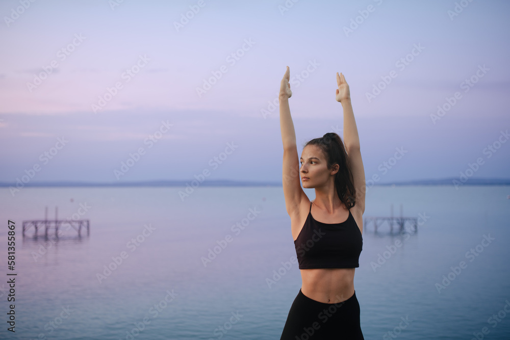 Young beautiful sportive girl meditating at early morning by the lake. Young beautiful sportive girl meditating at early morning by the lake.