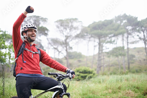 Pure exhilaration. A young male athlete pumping his fist in the air after conquering a mountain biking trail. photo