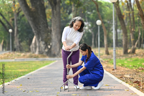 Attentive female caregiver helping, teaching senior woman to walking with walker. Assistance, rehabilitation and health