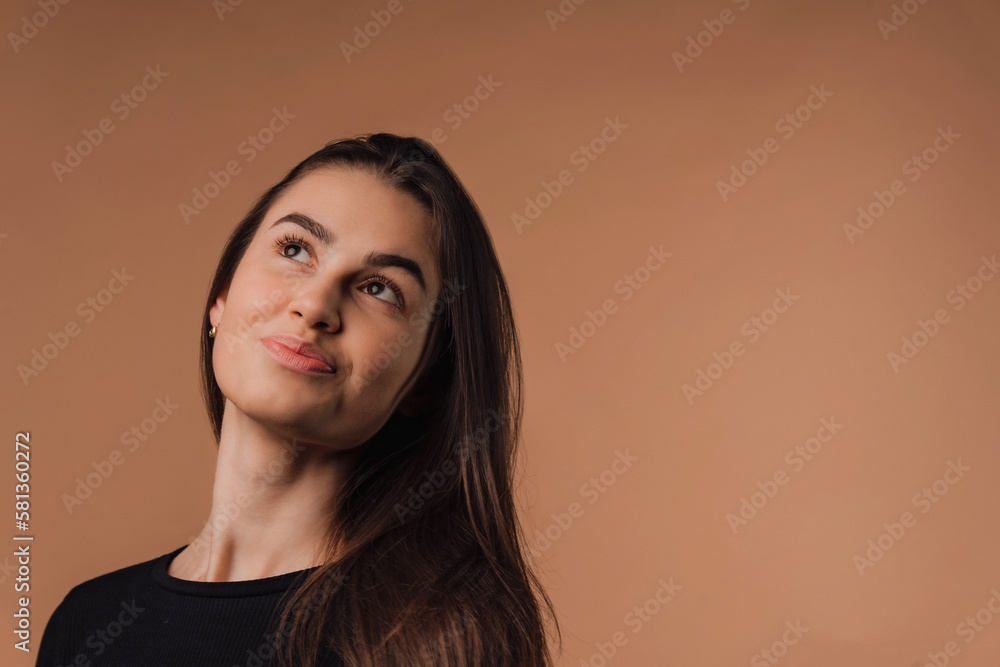 Fototapeta premium Portrait of young woman in studio, beige background.