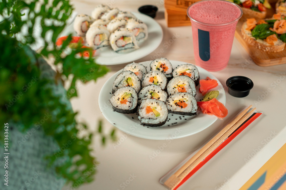 Fresh sushi maki with wasabi and ginger in wooden table with drinks