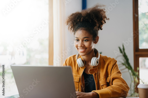 Attractive African woman smiling thinking planning writing in notebook, tablet and laptop working from home, at office