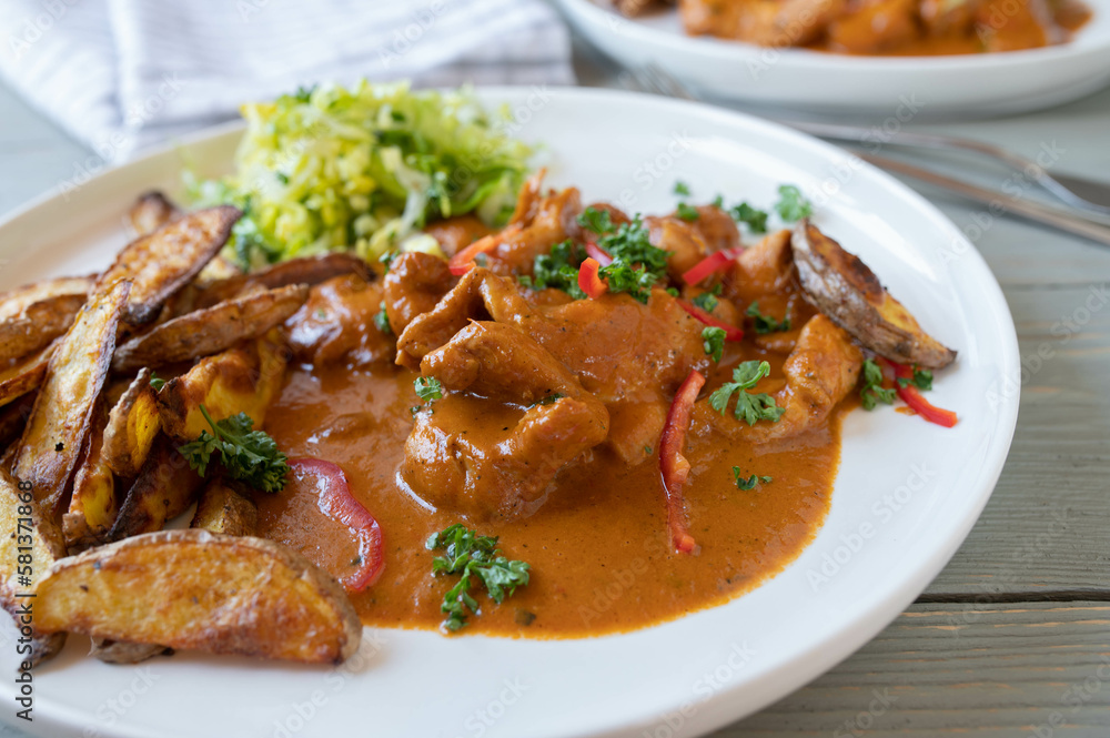 Chicken with paprika cream sauce, potato wedges and salad on a plate. Closeup Chicken with paprika cream sauce, potato wedges and salad on a plate. Closeup