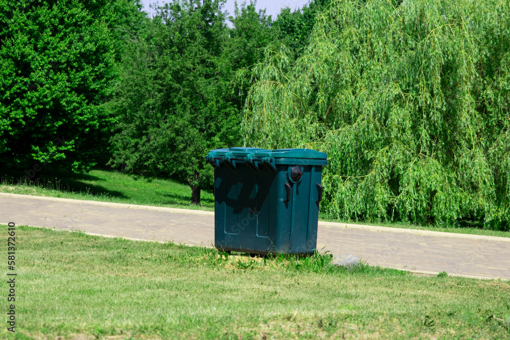 Plastic trash container in a city park on a summer sunny day Plastic trash container in a city park on a summer sunny day
