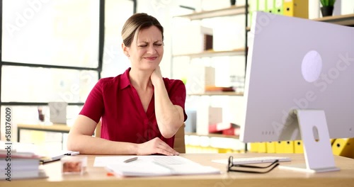 Tired unhealthy woman sitting at computer rubbing neck and feeling pain from osteochondrosis photo