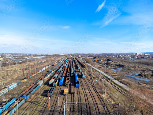Obraz na płótnie Aerial view landscape. View of railroad tracks and trains, cars, cargo. Blue sky. w salonie