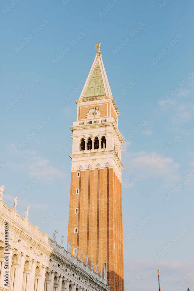 Beautiful buildings in Venice glows in bright sunlight. The tower watches over the city as if it waits for countless people to visit it.