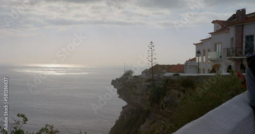 Cliff edge overlooking ocean on cloudy day in town of Nazare, Portugal. photo