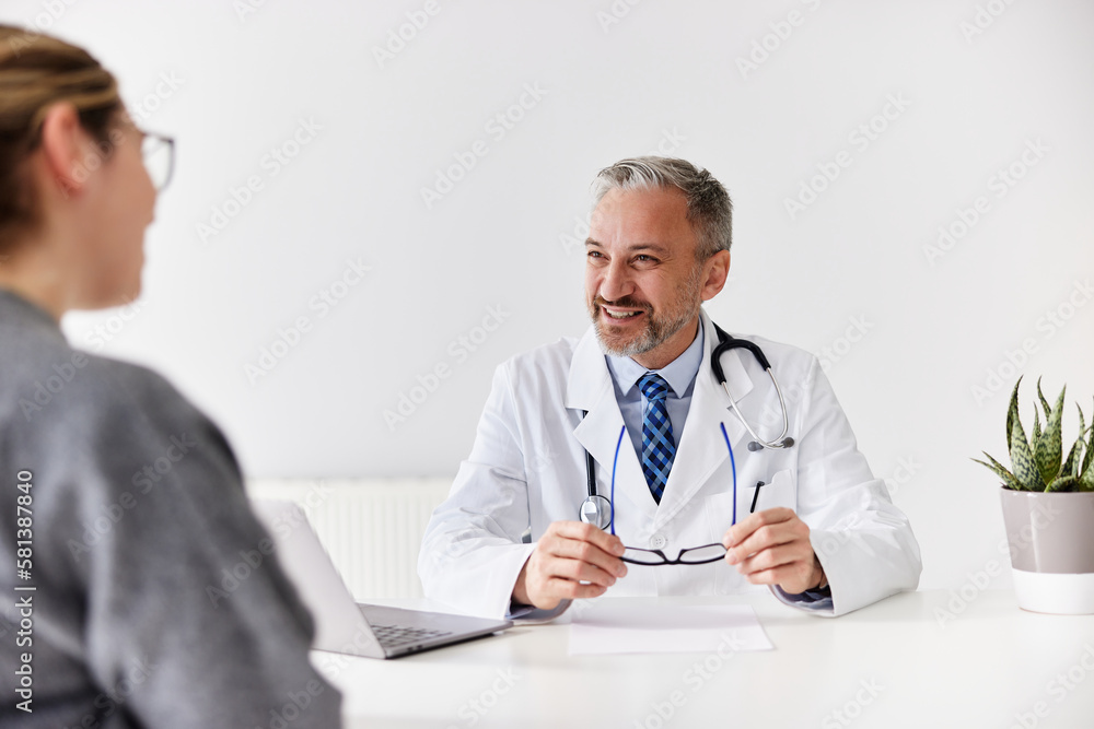 A smiling male doctor sitting with his female patient at his office. A smiling male doctor sitting with his female patient at his office.