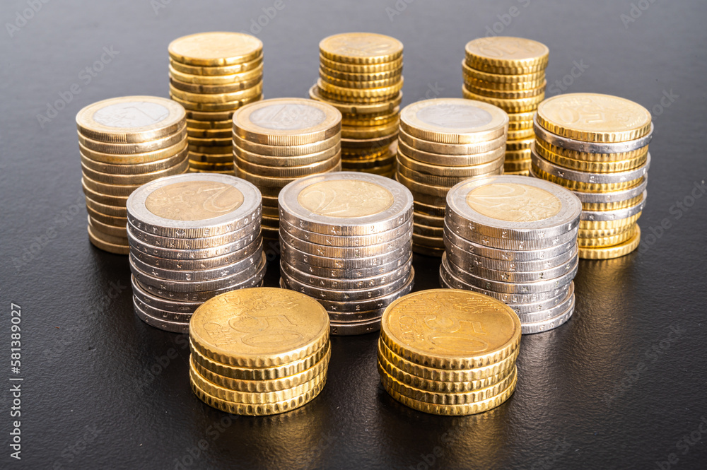 Stacks of coins next to each other, on black surface. Amount of money and wealth.
Stacks of coins next to each other, on black surface. Amount of money and wealth.