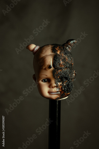 Damaged Dirty burnt Doll head on grey background © Mk16.15