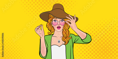 Surprised pop art woman in hat and glasses showing product Beautiful curly-haired woman presenting your product Yellow background from facial expressions