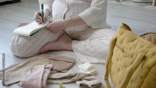 A Pregnant Woman Collects and Packs Clothes for her Newborn Baby photo