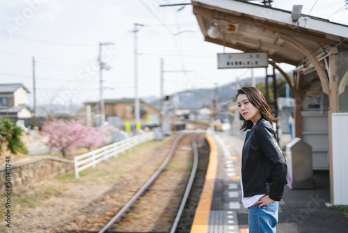 ローカル線の無人駅にいる女性 © peach100