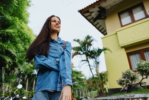 Portrait woman brunette smile with teeth running down the street against backdrop of palm trees in the tropics, summer vacations and outdoor recreation, the carefree lifestyle of a freelance student.