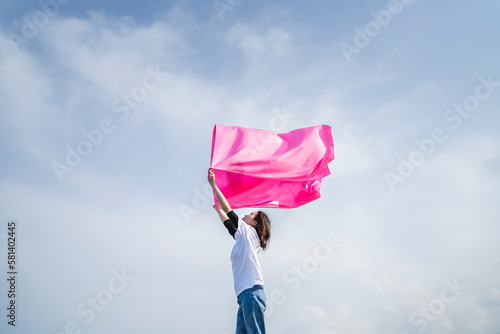 青空とピンクの布を持った女性