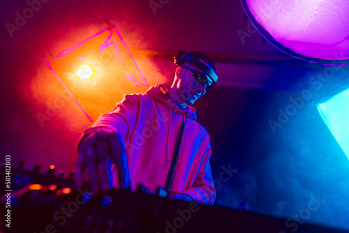 Male DJ playing music in the night club photo
