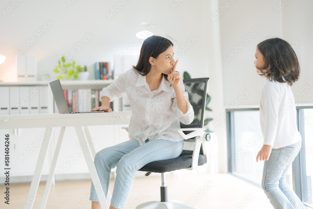 Obraz premium Mother trying to work at home office and daughter.