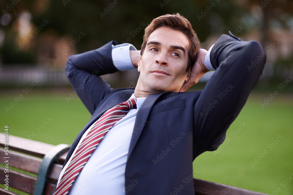 Taking a breather. A content businessman sitting with his hands behind his head on a park bench. Taking a breather. A content businessman sitting with his hands behind his head on a park bench.