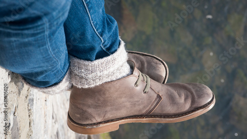 Botas de piel, calcetín y pantalón vaquero sobre lago photo