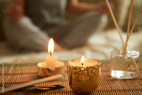 Close-up of scented candle, diffuser. A woman sits in a lotus position, meditates.