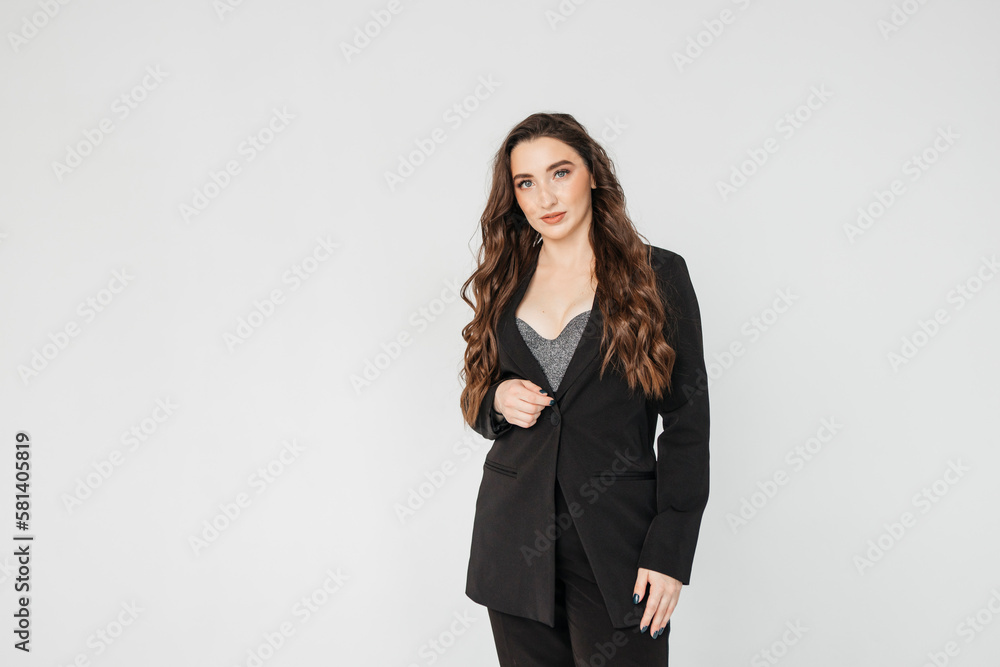 young businesswoman with long curly hair in a black suit stands on a white background young businesswoman with long curly hair in a black suit stands on a white background