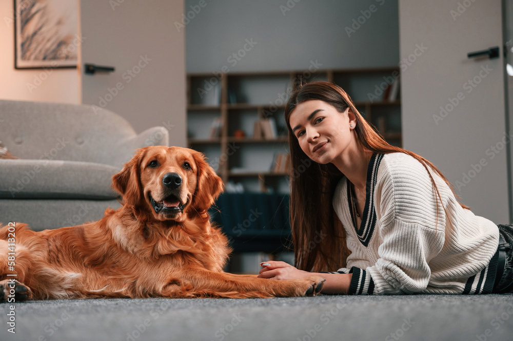 Cute golden retriever is in domestic room with his owner, beautiful young woman Cute golden retriever is in domestic room with his owner, beautiful young woman