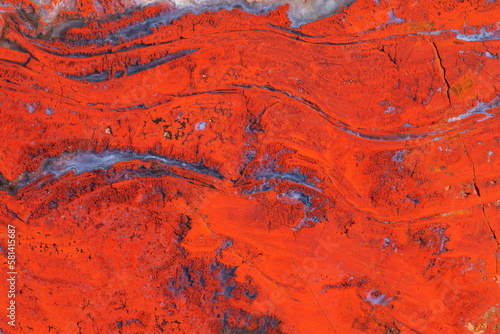 Full-screen texture of natural red jasper with wavy veins of blue chalcedony.
