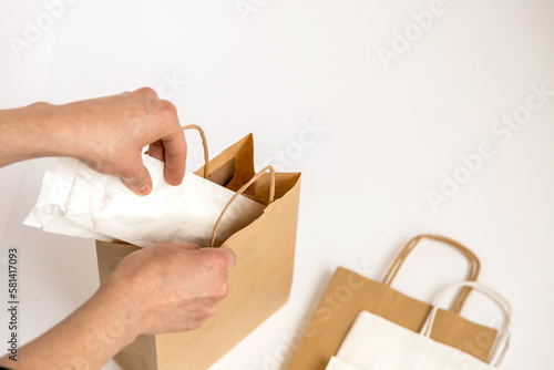 Action, person putting things inside kraft paper bag. Conceptual image of food delivery, ready-to-eat food, sustainability and recycling. Zero plastic concept, environmental concern. Copy space
