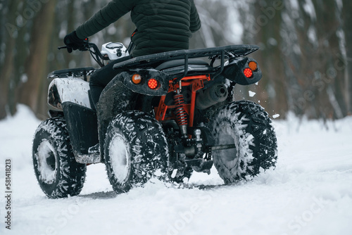 Snow, trees, adventure. Man is riding ATV outdoors in the winter forest
