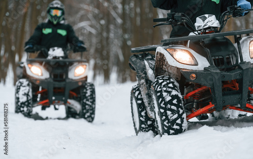 Man and woman are riding ATV in the winter forest