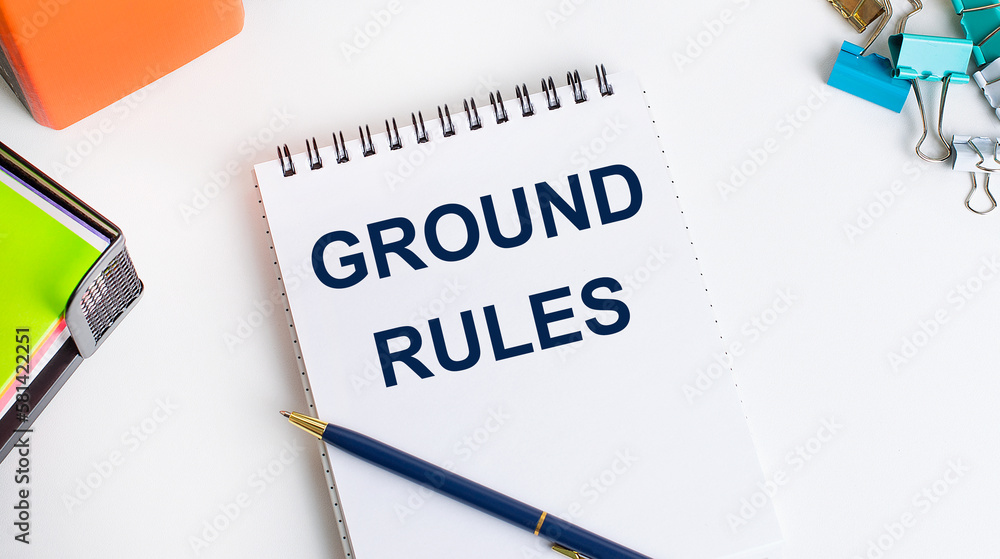 Office worker's desk, notepad with GROUND RULES text, pen, stationery Office worker's desk, notepad with GROUND RULES text, pen, stationery
