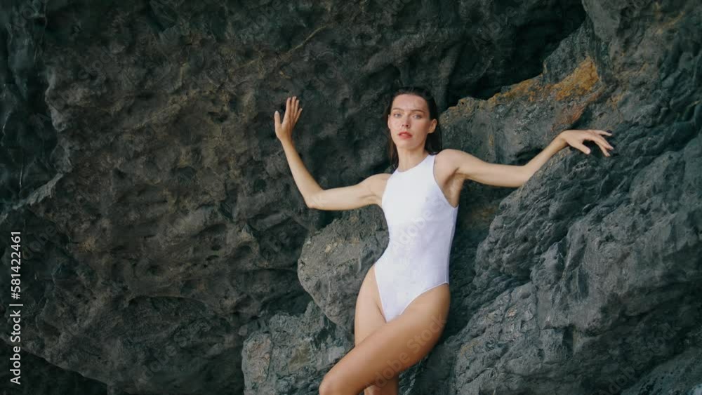 Hot woman posing swimsuit leaning on beach rock. Sexy girl looking seductively. Hot woman posing swimsuit leaning on beach rock. Sexy girl looking seductively.