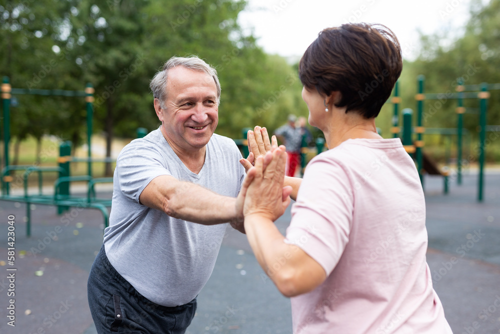 Friendly family couple doing gymnastic exercises together in summer city park Friendly family couple doing gymnastic exercises together in summer city park