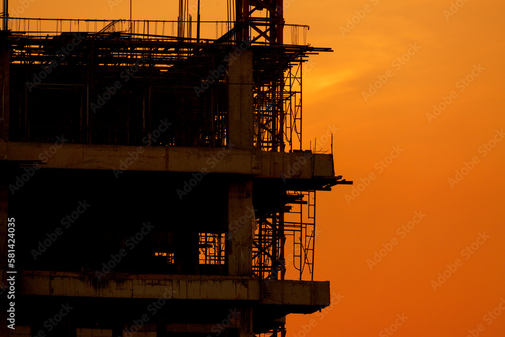 Silhouette construction site on sunset in evening time.Engineer and worker on building site.Construction sites and cranes are working in the industry new building business. Silhouette construction site on sunset in evening time.Engineer and worker on building site.Construction sites and cranes are working in the industry new building business.