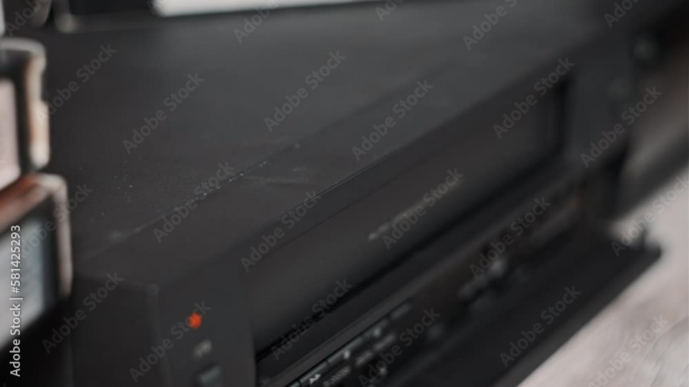 Eject VHS tape cassette from VCR player. Male hand pulls out VHS from a