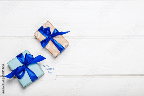 Gift boxes with satin blue bows on a white wooden background. The concept of celebrating father s day.