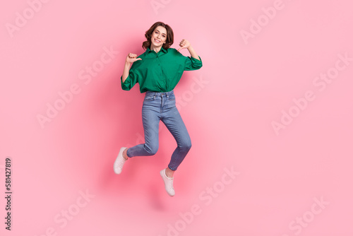 Full length photo of cute excited lady dressed green blouse pointing thumbs herself jumping emtpy space isolated pink color background