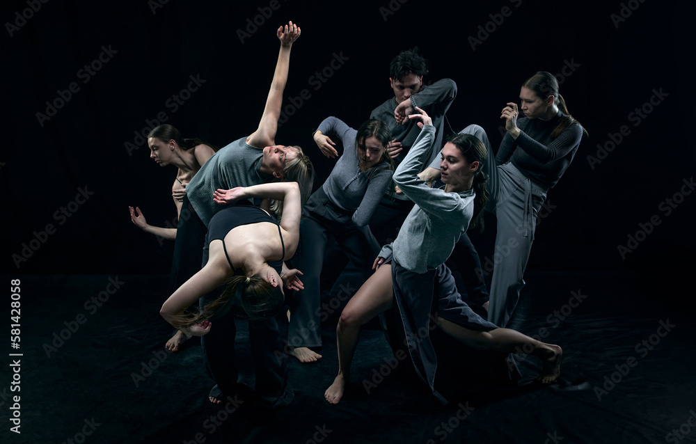 Self-expression through moves. Group of young people dancing against black studio background. Concept of modern freestyle dance, contemporary art, movements, hobby and creative lifestyle