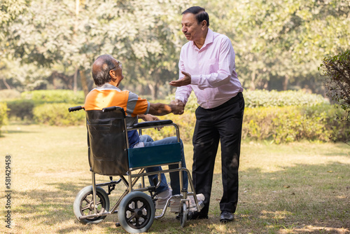Senior friends meeting in a park and greeting each other, disabled person, wheelchair