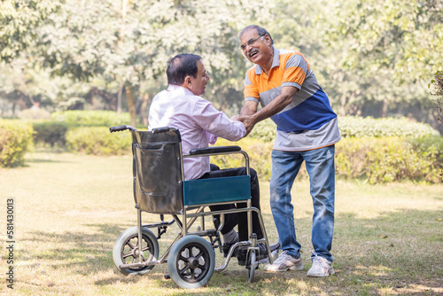 Senior friends meeting in a park and greeting each other, disabled person, wheelchair