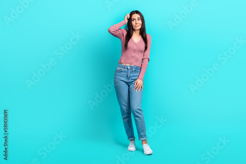 Full length portrait of minded clueless young person arm fingers scratch head look empty space isolated on teal color background