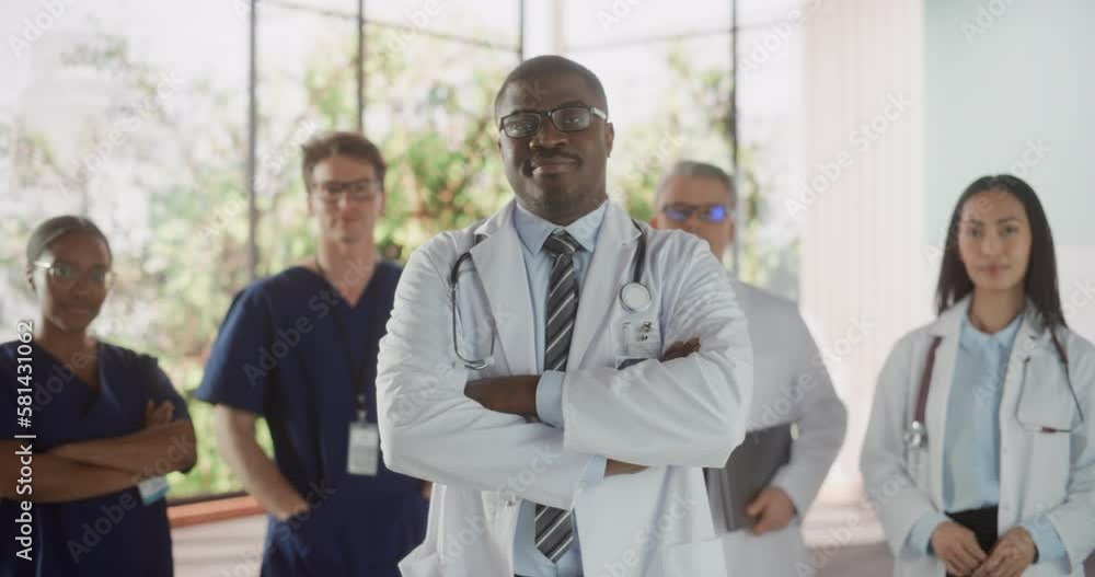 Team Portrait of a Female and Male Successful Diverse Medical Healthcare Professionals Standing as a Group in a Modern Hospital Office. African American Doctor Standing Closer to Camera Team Portrait of a Female and Male Successful Diverse Medical Healthcare Professionals Standing as a Group in a Modern Hospital Office. African American Doctor Standing Closer to Camera
