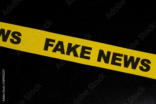 Fake news alert, caution, warning and investigation concept. Yellow barricade tape with word in dark black background. photo