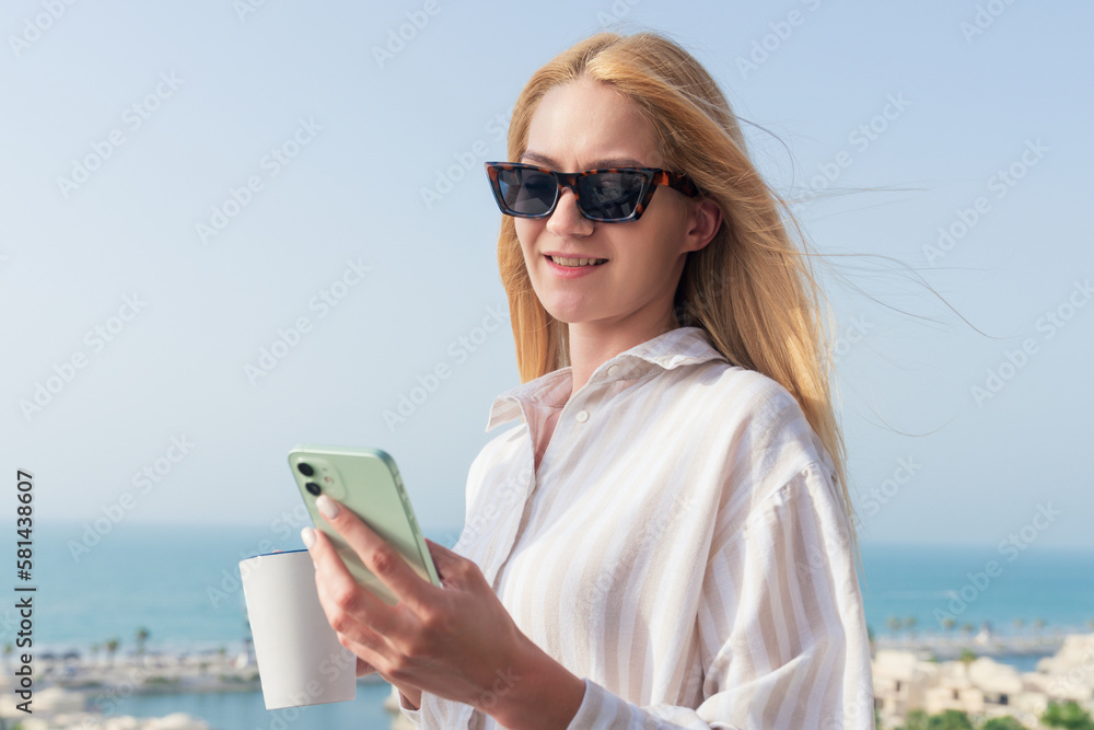 Portrait of a young woman with a coffee mug and a phone during a summer vacation